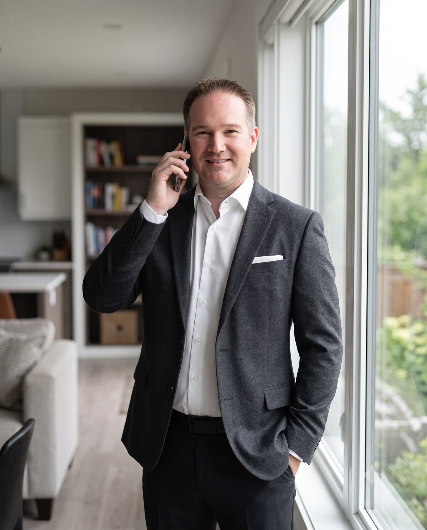 Dave Maund taking a call at the window of a bright living room